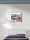 Framed artwork of a bridge over water on a wall above a bed.