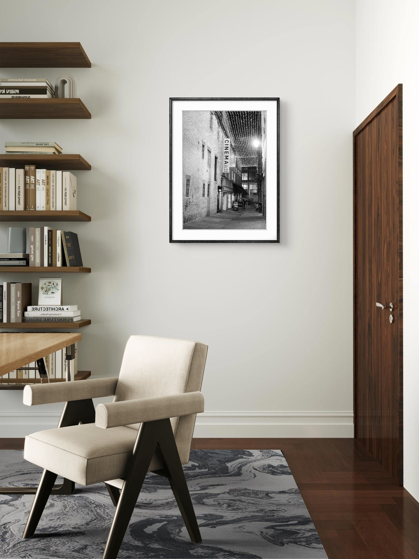 Modern interior with a chair, bookshelf, and framed picture on the wall.