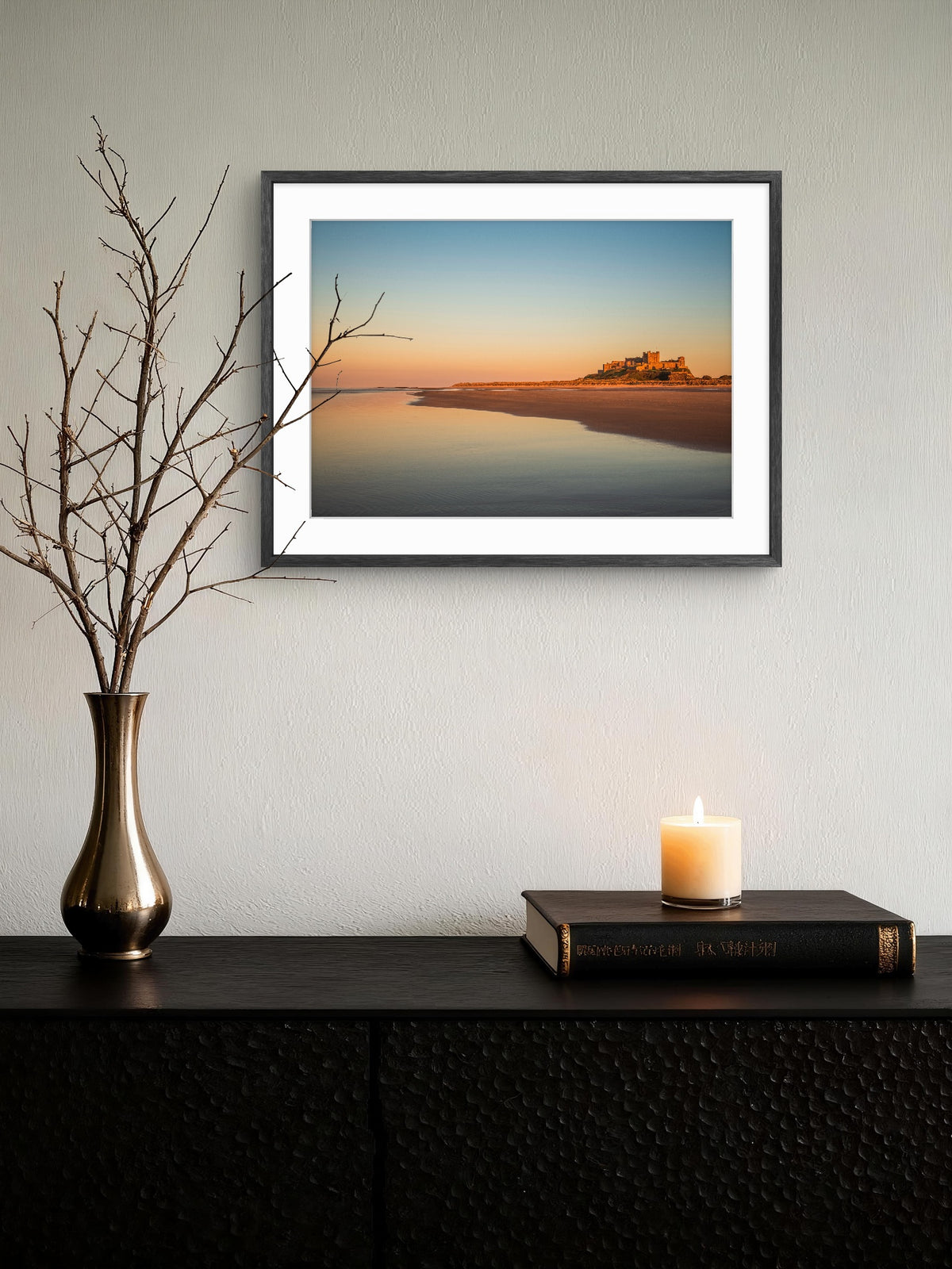 Framed artwork of a sunset over water on a wall above a console table with decorative items.