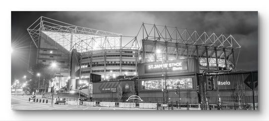 Black and white panoramic photograph of St James' Park stadium at night in Newcastle.