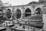 Rowboats moored under a stone bridge with arches over water