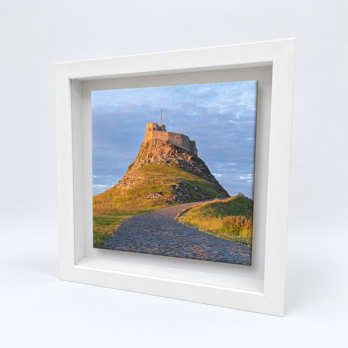 Lindisfarne Castle on an 8×8 inch ceramic tile in a white box frame, angled view