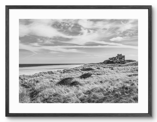 Black-and-white Bamburgh Castle beach and dunes shown as a framed photographic print.
