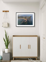 Framed artwork of a coastal scene above a white cabinet with wooden accents.