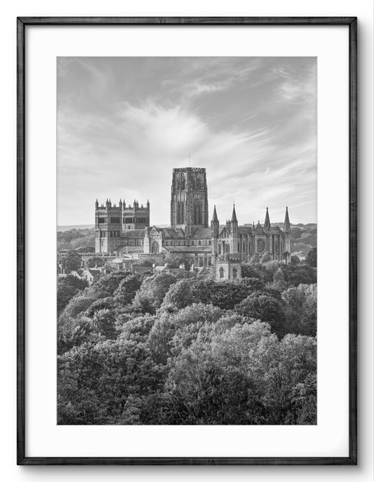 Black-and-white photograph of Durham Cathedral surrounded by trees with a white border.