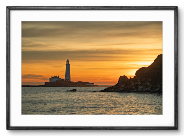 Lighthouse on an island with a colorful sunset sky, framed picture.