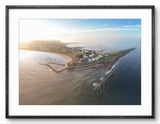 Aerial view of a coastal area with houses and a lighthouse, framed in black.
