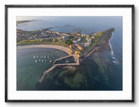 Aerial view of a coastal town with a pier and boats, framed in black.