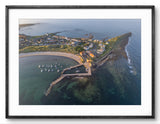 Aerial view of a coastal town with a pier and boats, framed in black.