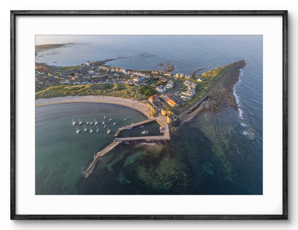 Aerial view of a coastal town with a pier and boats, framed in black.
