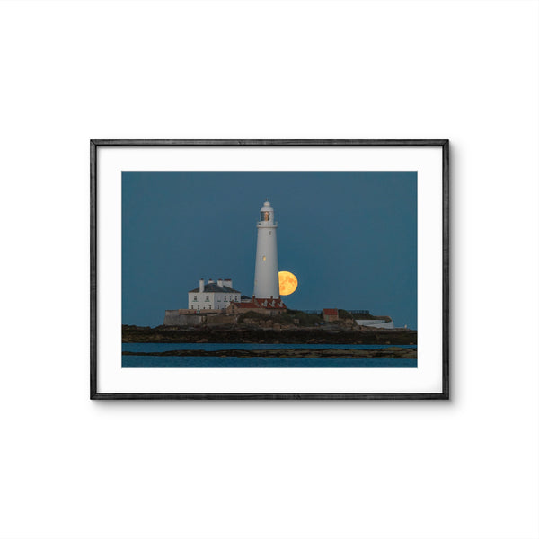 Framed photograph of a lighthouse with a moonlit sky