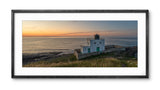 Framed photograph of a lighthouse at sunset with a black frame.