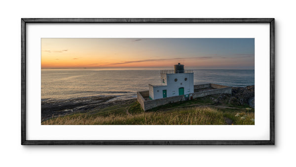 Framed photograph of a lighthouse at sunset with a black frame.