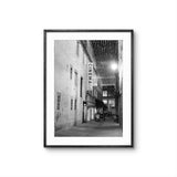 Framed black and white photo of a city street with a cinema sign.