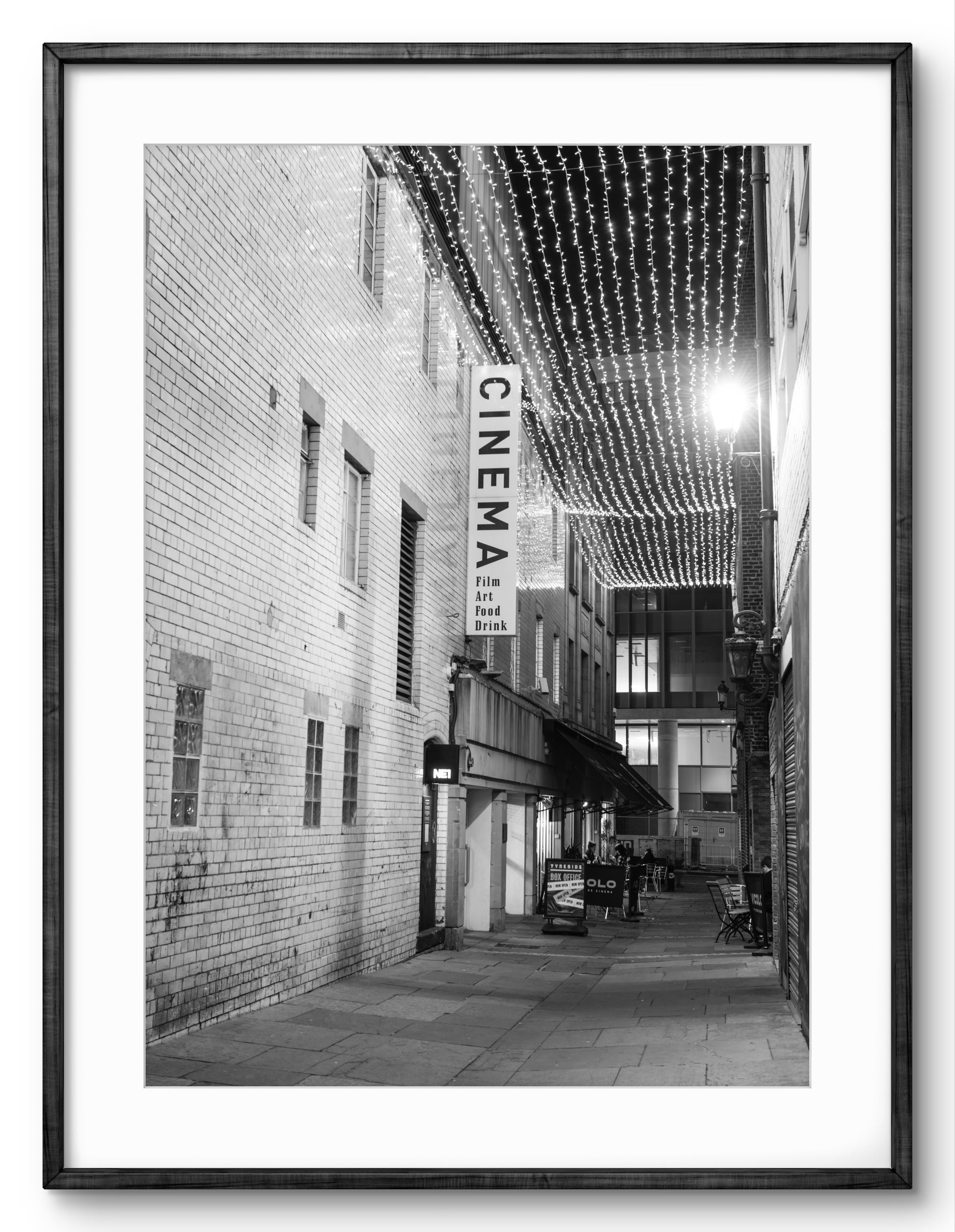 Framed black and white photo of a city street with a cinema sign.