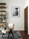 Modern interior with a chair, bookshelf, and framed picture on the wall.