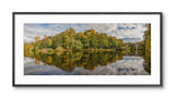 Framed panoramic landscape of a lake with trees and a bridge
