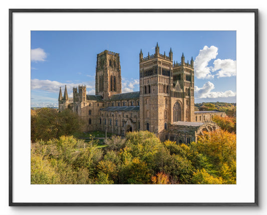 Large cathedral with tall spires surrounded by trees under a blue sky.