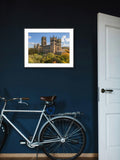 Framed picture of a cathedral on a blue wall with a bicycle below
