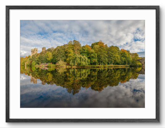 Framed photograph of a scenic landscape with trees and a castle reflected in water.