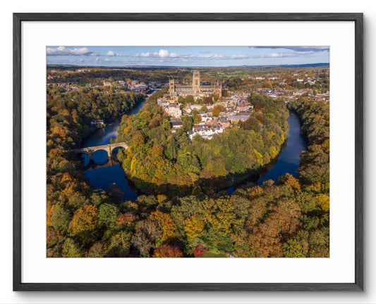 Aerial view of a castle surrounded by trees with autumn foliage.