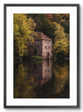 Framed photograph of a stone building reflected in water surrounded by trees