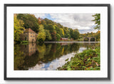 Framed photograph of a serene landscape with a river, bridge, and trees.