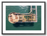 Aerial view of a rusted metal structure in water, framed with a black border.