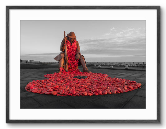 Person sitting on a large arrangement of red stones with a black frame.