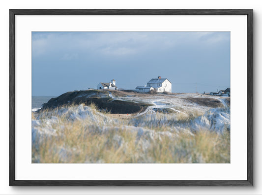 Framed photograph of a coastal scene with houses on a hill overlooking the ocean.