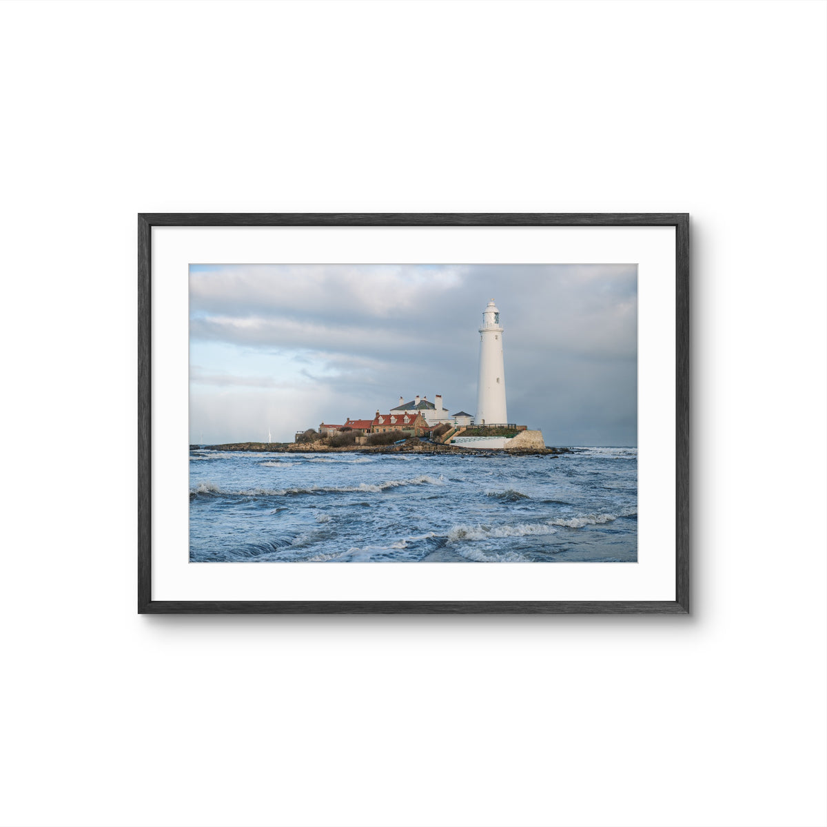 Framed photograph of a lighthouse on an island with choppy waters and a cloudy sky.