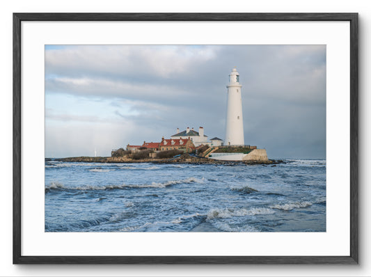 Lighthouse on a rocky island with waves in the foreground, framed picture.