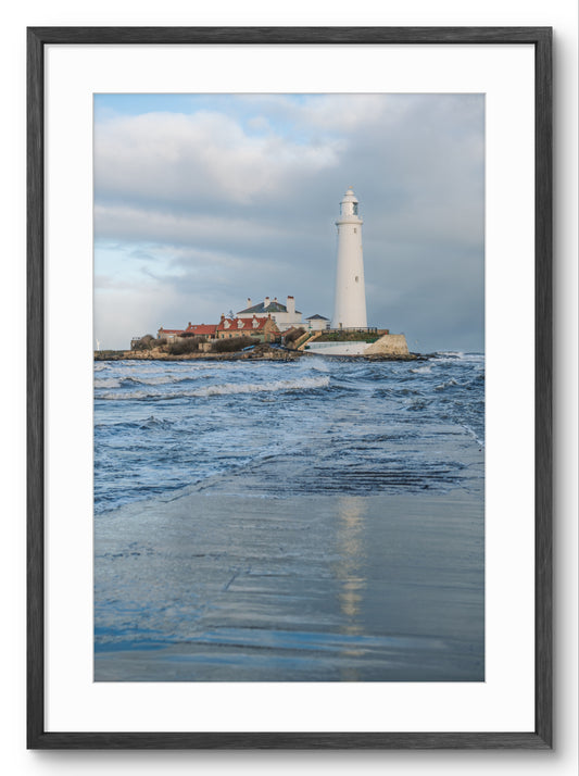 Framed photograph of a lighthouse on an island with blue water and sky.