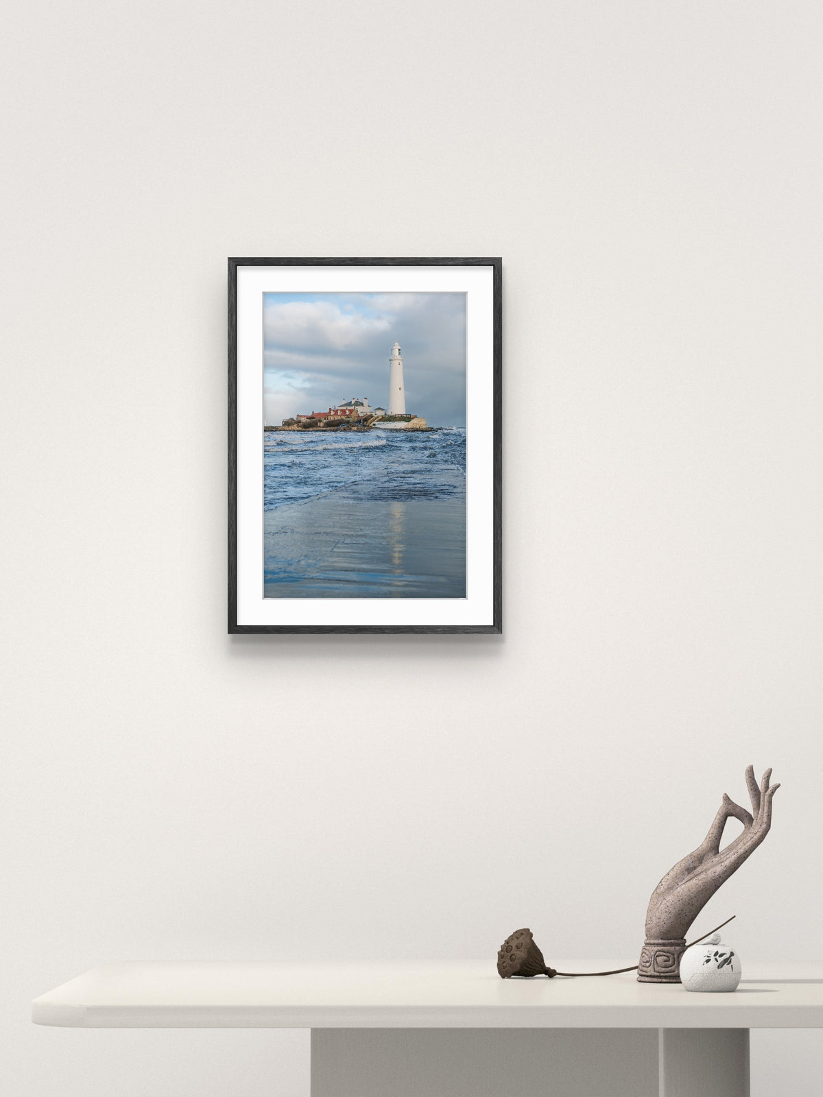 Framed photograph of a lighthouse on a wall above a white table.