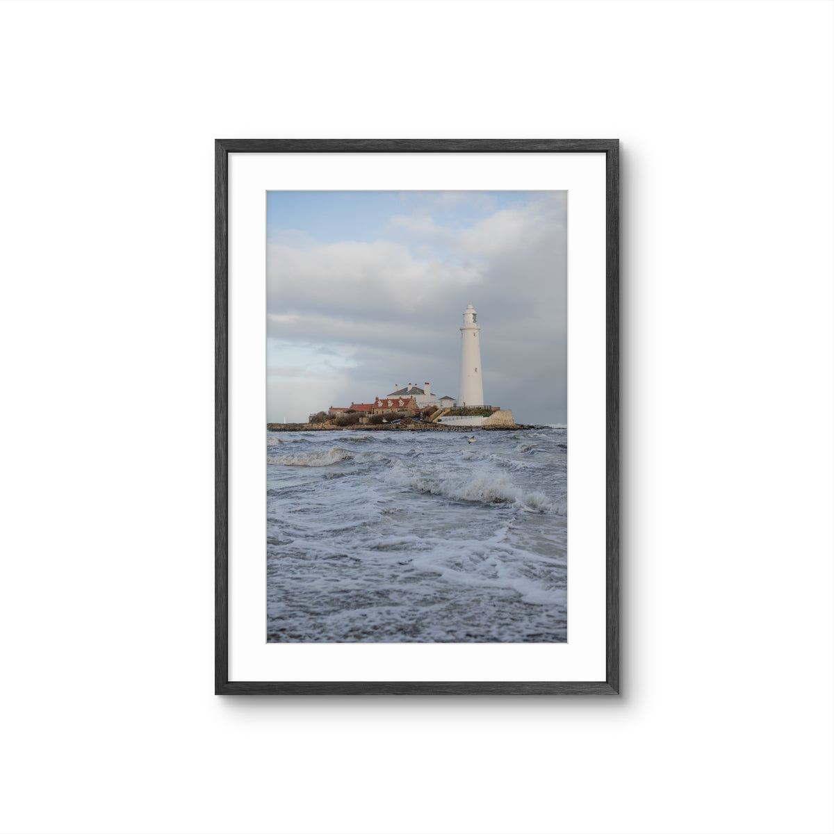 Framed photograph of a lighthouse on an island with waves in the foreground