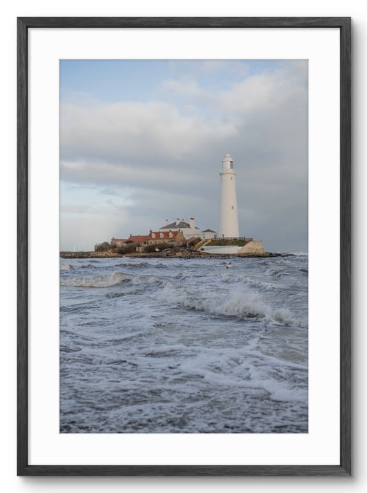Lighthouse on a rocky island with waves in the foreground, framed picture.