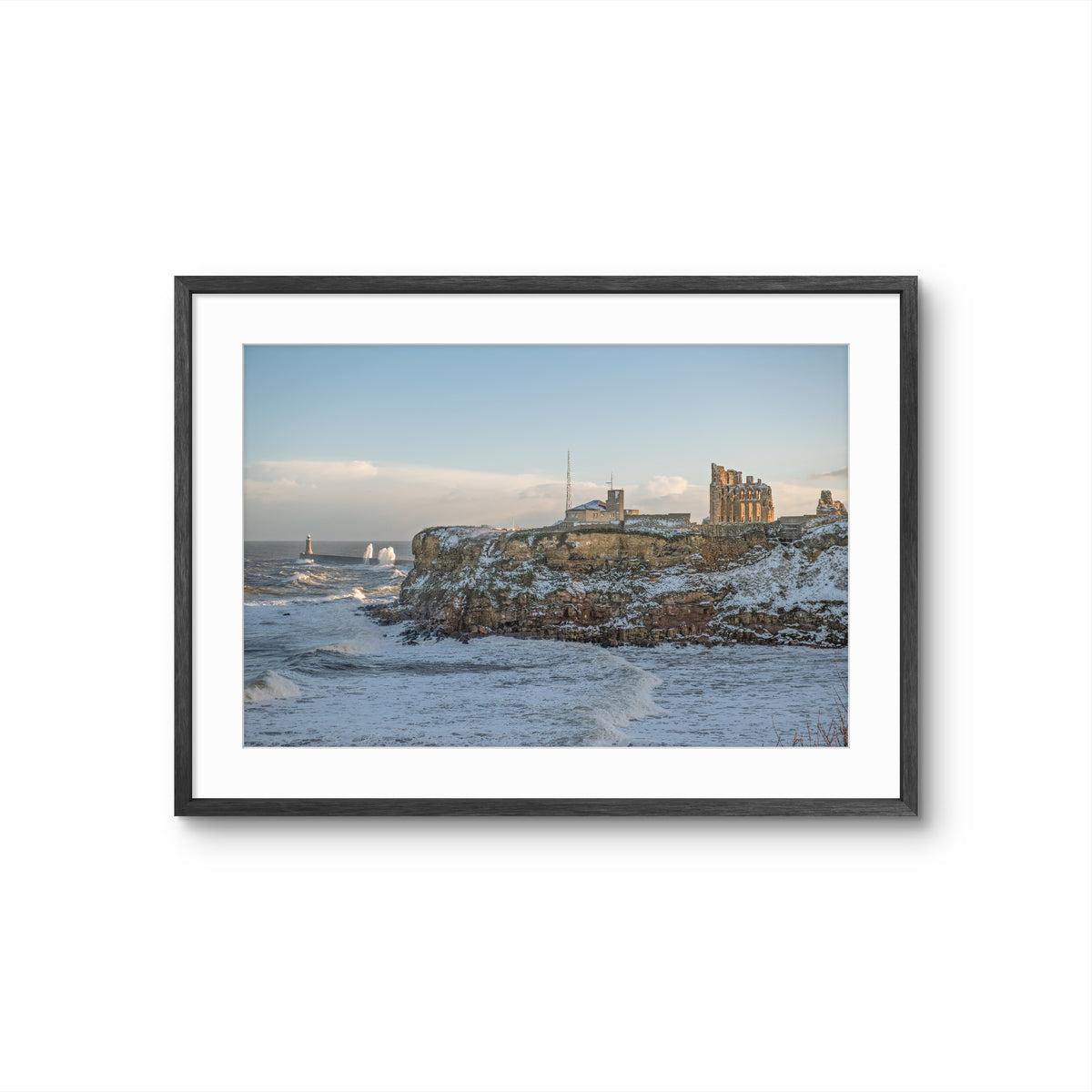 Framed photograph of a coastal scene with a castle on a cliff overlooking the sea.