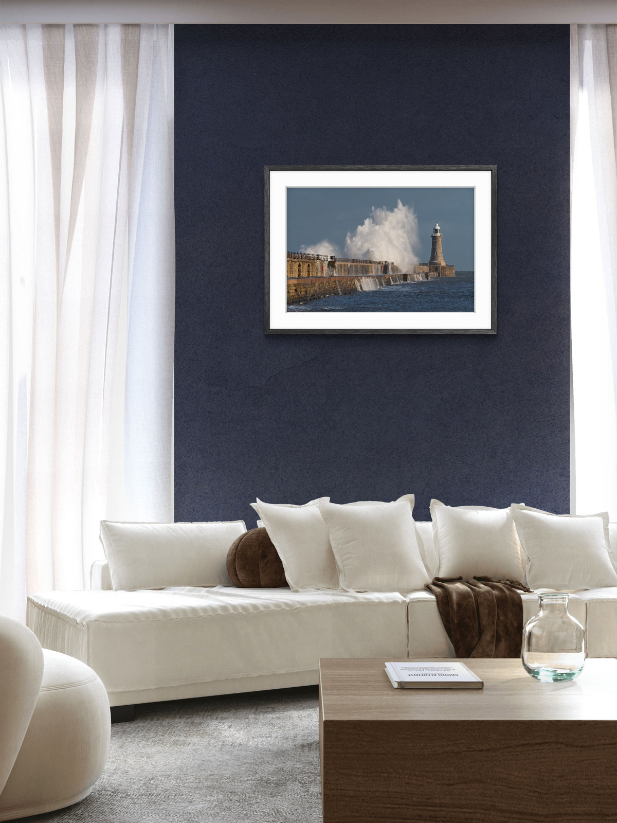 Living room with a white sofa, coffee table, and framed picture of a lighthouse on a blue wall.
