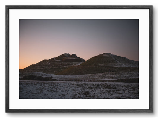 Framed photograph of a mountain landscape with a sunset or sunrise.