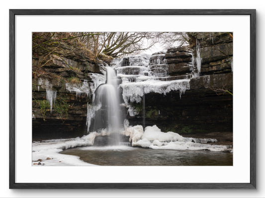 Framed photograph of a frozen waterfall with ice formations.
