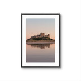 Framed photograph of a castle on an island with a reflective water surface and pastel sky.