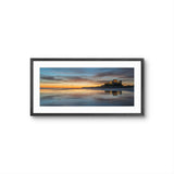Framed artwork of a sunset over a castle on an island with a reflective water surface.