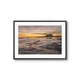 Framed photograph of a sunset over water with a ship in the distance on a white background