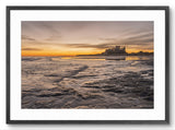 Framed photograph of a sunset over a coastal landscape with a castle.