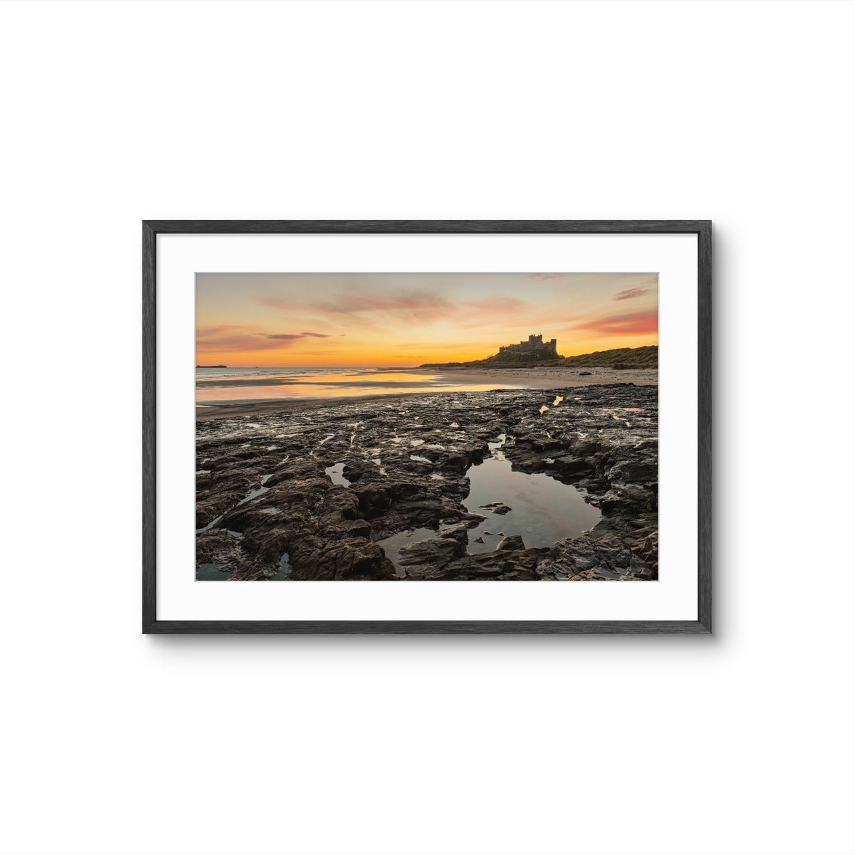 Framed photograph of a coastal scene with a sunset and a castle on a hill.
