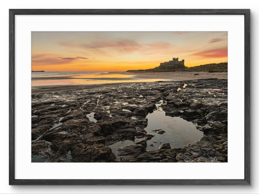 Framed photograph of a sunset over a coastal landscape with a castle.