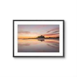 Bamburgh Castle reflected on wet sand at sunrise on the Northumberland coast
