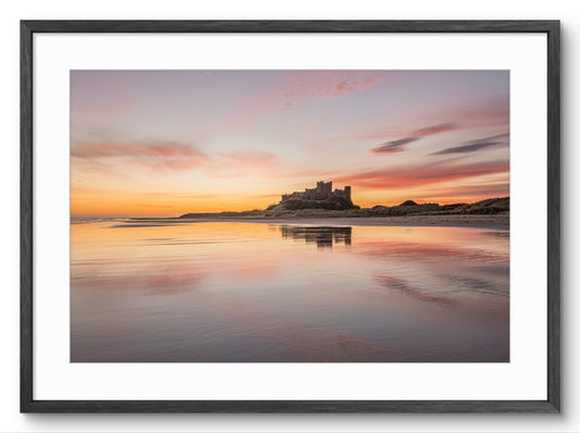 Bamburgh Castle reflected on wet sand at sunrise on the Northumberland coast
