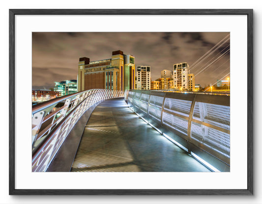 Cityscape at night with illuminated buildings and a bridge.