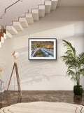 Framed artwork on a wall with a plant and floor lamp in a modern interior setting